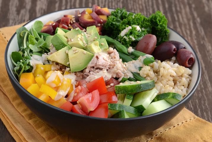 Healthy Buddha-style bowl with veggies, brown rice, tuna and tahini dressing