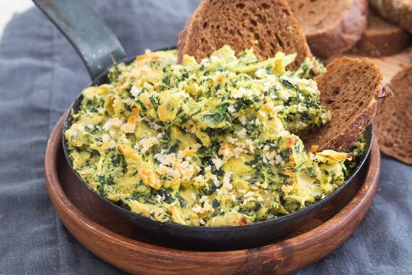 Vegan creamy artichoke dip in a bowl with bread slices