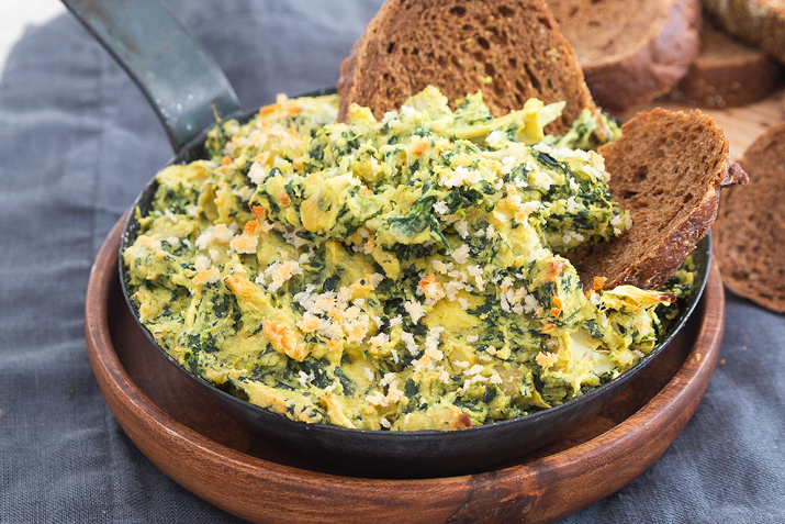 Vegan creamy artichoke dip in a bowl with bread slices